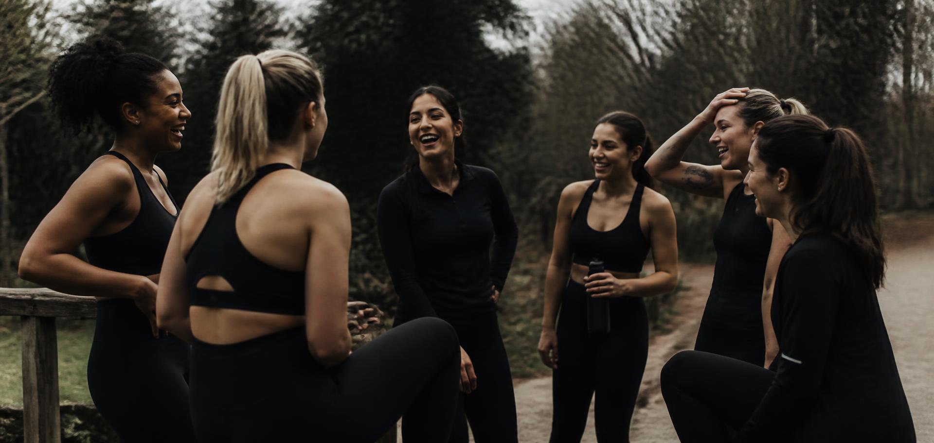 Comunidade de mulheres reunidas ao ar livre após o treino